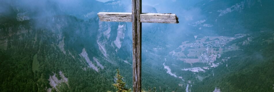 photo of brown wooden cross at cliff